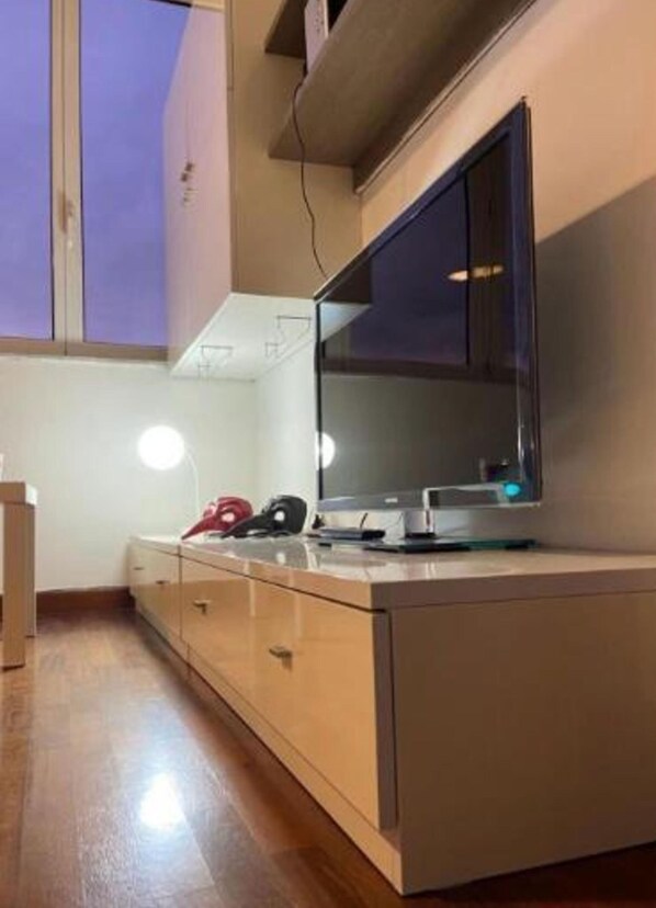 A modern kitchen with a large flat-screen TV, wooden cabinets, and a built-in oven. - Casa Roma Apartment in Albenga (Albenga)