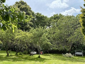 A lush garden with a variety of trees and a small seating area with a table and chairs. - Spacious Home with Garden, WiFi, and Games Room Near Dordogne's Best Sights (Payzac)
