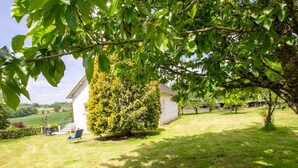 A house with a well-maintained lawn, a tree in the foreground, and a clear view of the surrounding countryside. - Spacious Home with Garden, WiFi, and Games Room Near Dordogne's Best Sights (Payzac)