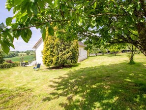 A house with a well-maintained lawn, a tree in the foreground, and a clear view of the surrounding countryside. - Spacious Home with Garden, WiFi, and Games Room Near Dordogne's Best Sights (Payzac)