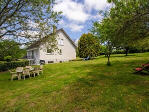 A house with a front porch, a dining area with chairs, and a lawn. - Spacious Home with Garden, WiFi, and Games Room Near Dordogne's Best Sights (Payzac)