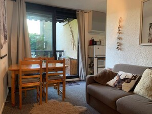 A cozy living room with a brown sofa, wooden dining table, and chairs. - Cozy studio 4 pers with balcony in Pra-Loup 1500 (Pra-Loup)