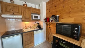 A compact kitchen with wooden cabinets, a microwave, a toaster, and a sink. - Super Duplex in Vars - 2 Bedrooms, Terrace, Parking (Vars)