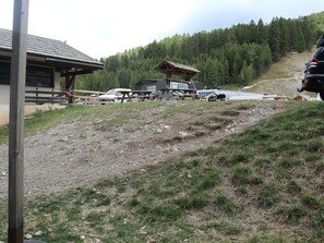 A rustic lodge with a wooden structure, a picnic table, and a car parked nearby. - Ski-in/Ski-out Apartment for 8 with Terrace and Stunning Views (Les Orres)
