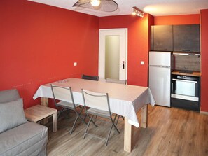 A compact kitchen with a refrigerator, oven, and a dining area with a table and chairs. - Ski-in/Ski-out Apartment for 8 with Terrace and Stunning Views (Les Orres)