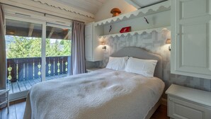Een slaapkamer met een groot bed, een raam met gordijnen, een balkon en een muur met decoratieve details.