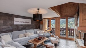 Een moderne woonkamer met een grijze bank, een houten salontafel en een open haard.