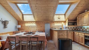 Een gezellige keuken met houten kastjes, een eethoek met een tafel voor vier personen, en dakramen erboven.