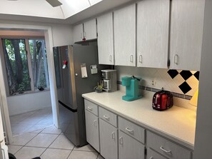 A modern kitchen with grey cabinets, a stainless steel refrigerator, a coffee maker, and a toaster.