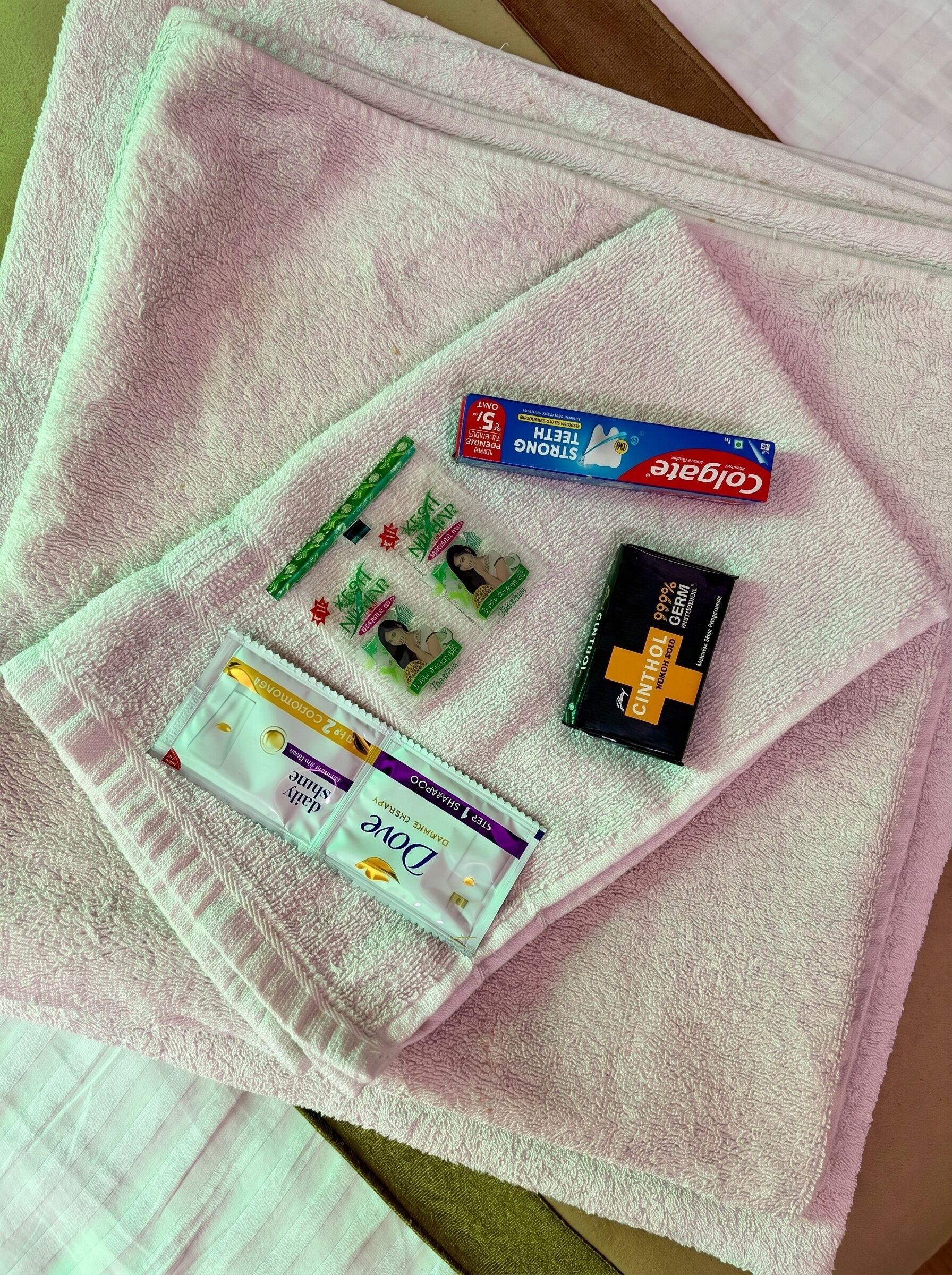 A pink towel with various personal care items including a toothbrush, toothpaste, and a pack of gum.