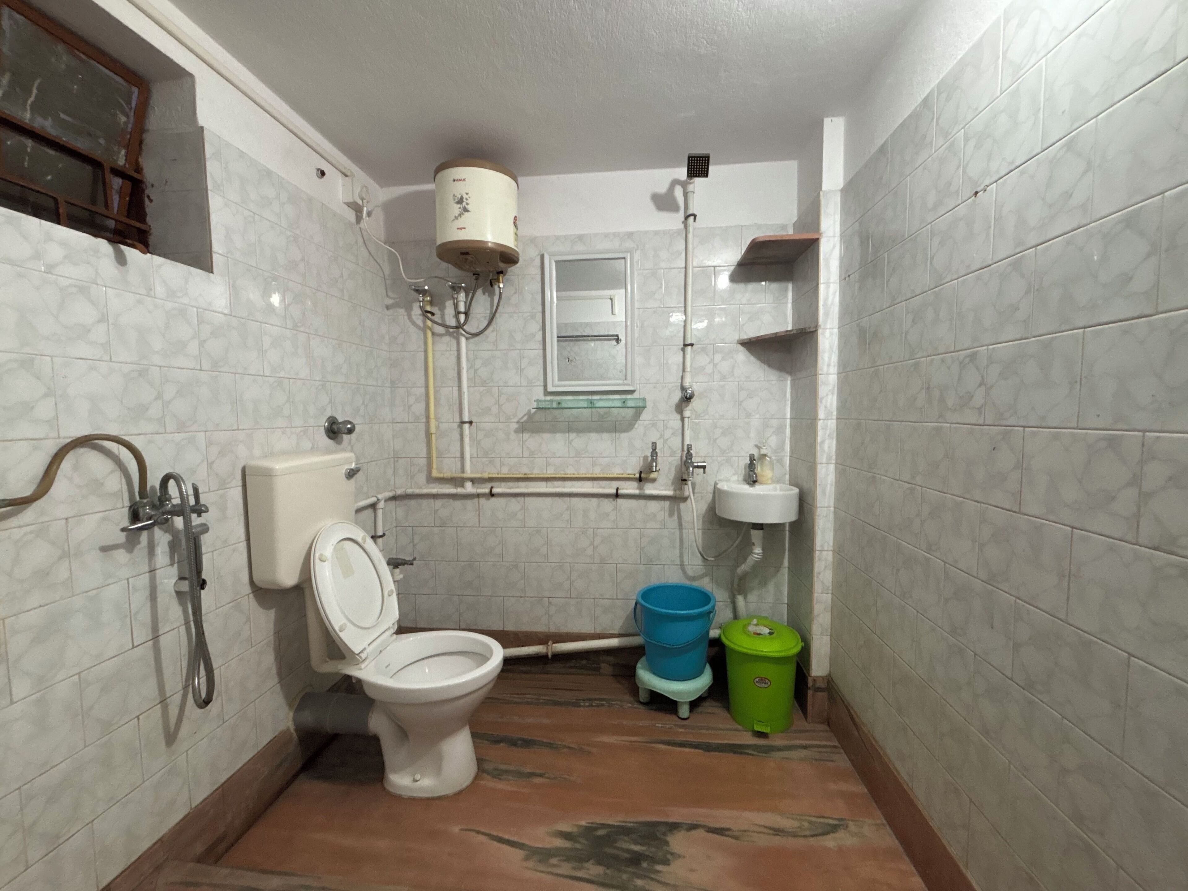 Une petite salle de bain comprenant des toilettes, un lavabo, une douche et un chauffe-eau.