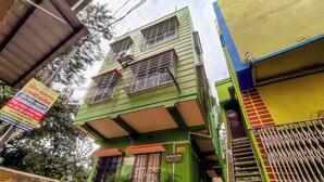 A multi-story building with a green facade, multiple balconies, and a sign indicating a Green Palace Guest House. - Green Place Guest House (Bankura)