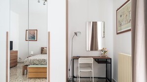 A bedroom with a bed, bedside table, chair, desk, and a mirror. - Bari Station Classic Apartment by Wonderful Italy (Bari)