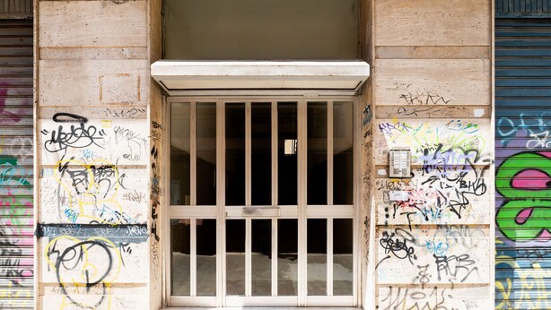 A building entrance with a barred door and walls covered in graffiti. - Bari Station Classic Apartment by Wonderful Italy (Bari)