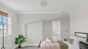 Une chambre à coucher avec un lit, une table de chevet, une lampe et une plante en pot.