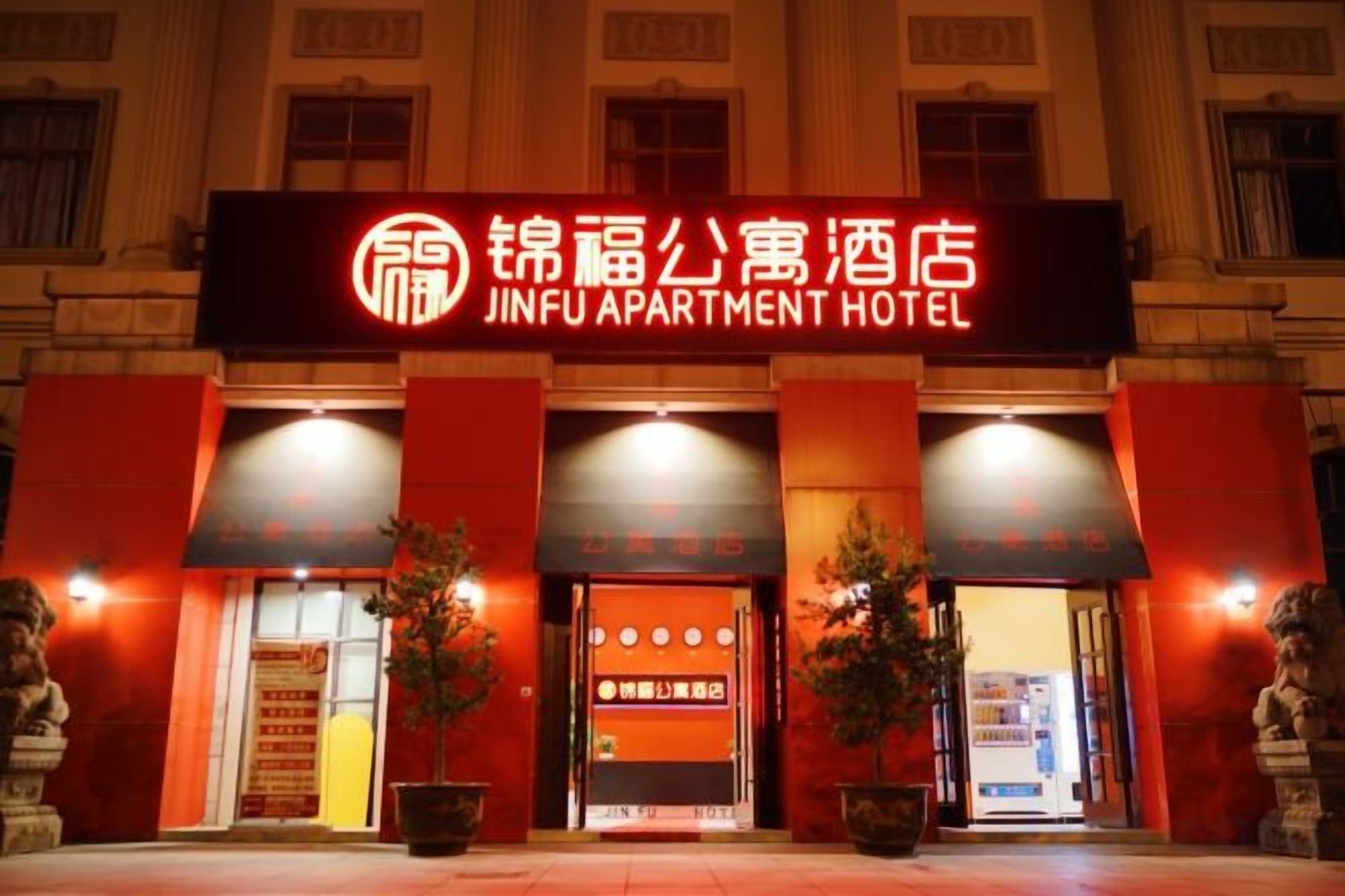 L’entrée d’un hôtel, avec une enseigne indiquant « JINFU APARTMENT HOTEL », et un style architectural chinois traditionnel.
