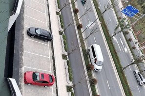 Una carretera con varios carriles, vehículos, aceras y un cartel direccional azul.