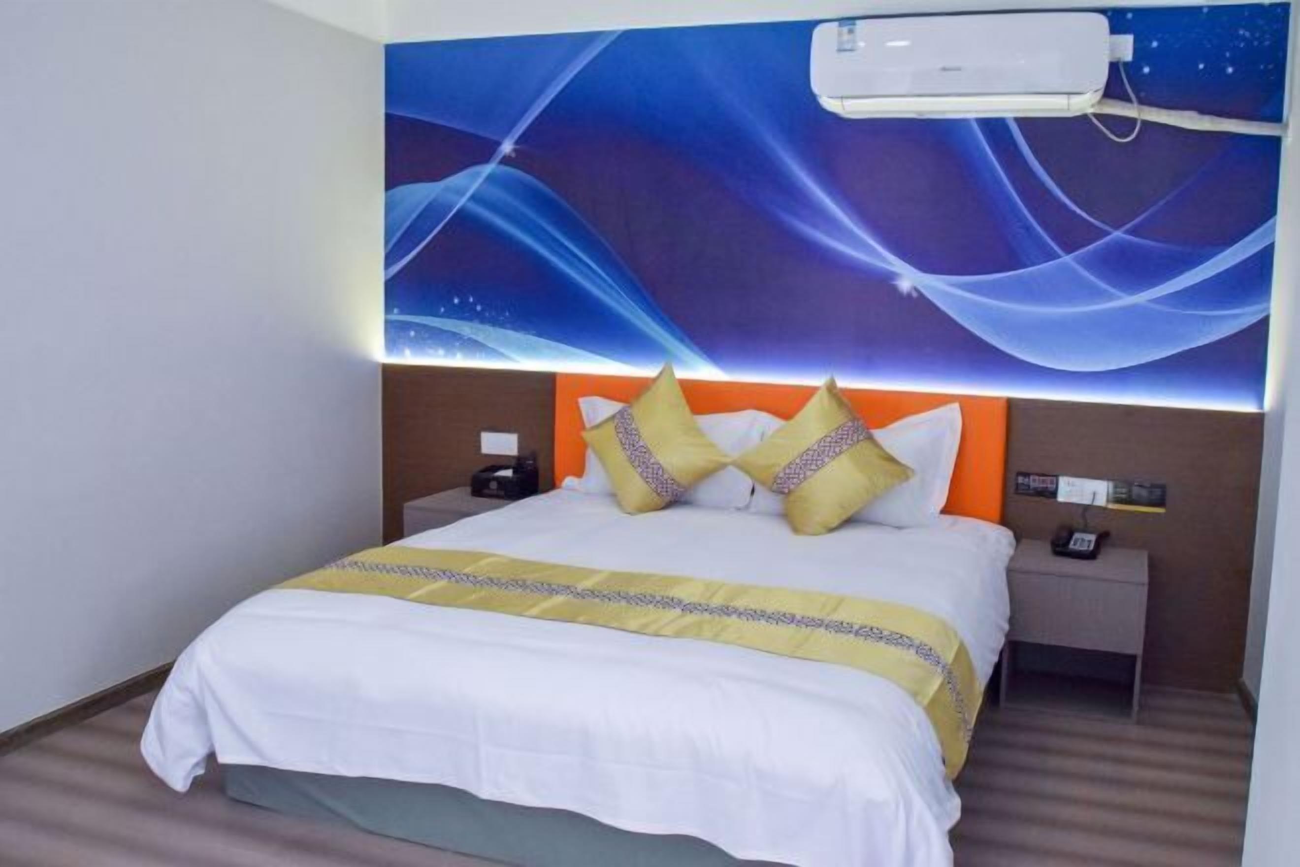 A hotel room with a bed, a nightstand, an air conditioning unit, and a wall with a space-themed mural.