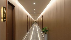 A long, well-lit hallway with doors marked by numbers, a polished floor, and a potted plant on the right. - Ningbo jinfu hotel apartment (Ningbo)
