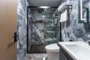 A modern bathroom with a glass-enclosed shower, a white sink, and a marble wall. - Ningbo jinfu hotel apartment (Ningbo)