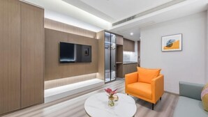 A modern living room with a sofa, a coffee table, and a TV mounted on the wall. - Ningbo jinfu hotel apartment (Ningbo)