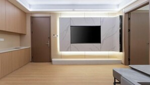 A modern room with a flat-screen TV mounted on a marble wall, wooden cabinets, and a bench. - Ningbo jinfu hotel apartment (Ningbo)