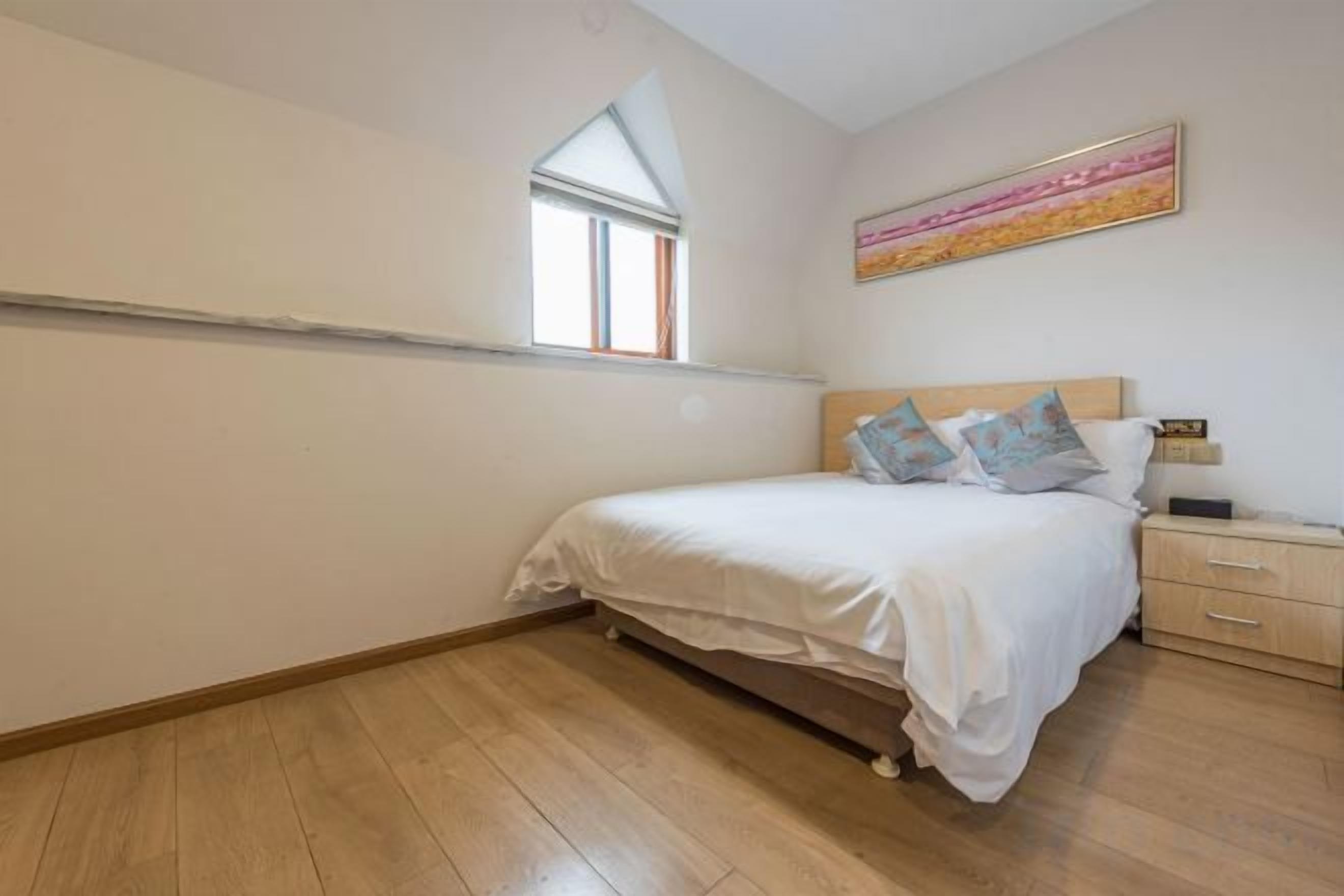 Un dormitorio con una cama individual, una mesita de noche, una ventana y un cuadro en la pared.