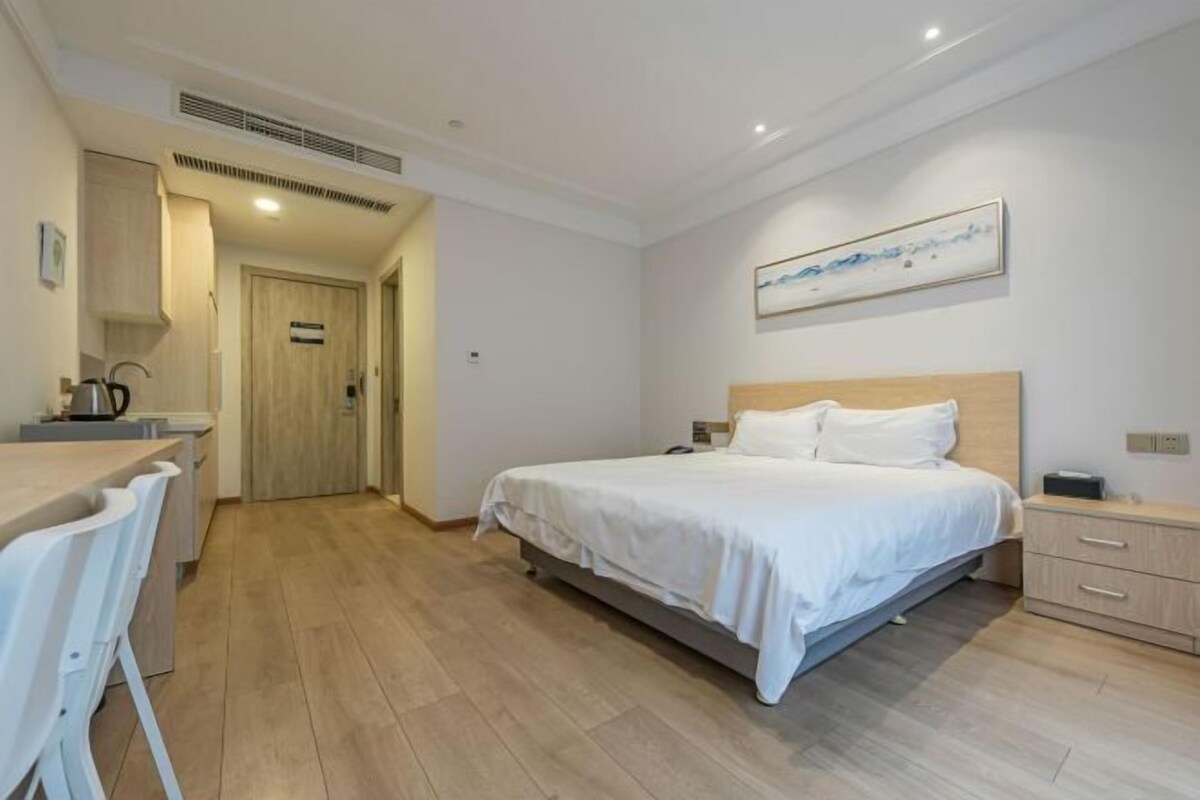 A bedroom with a bed, bedside table, and a painting on the wall.