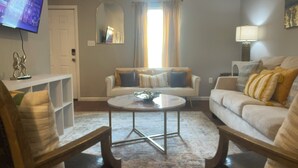 Ein Wohnzimmer mit zwei Sofas, einem Couchtisch, einem Fernseher und einer Lampe.