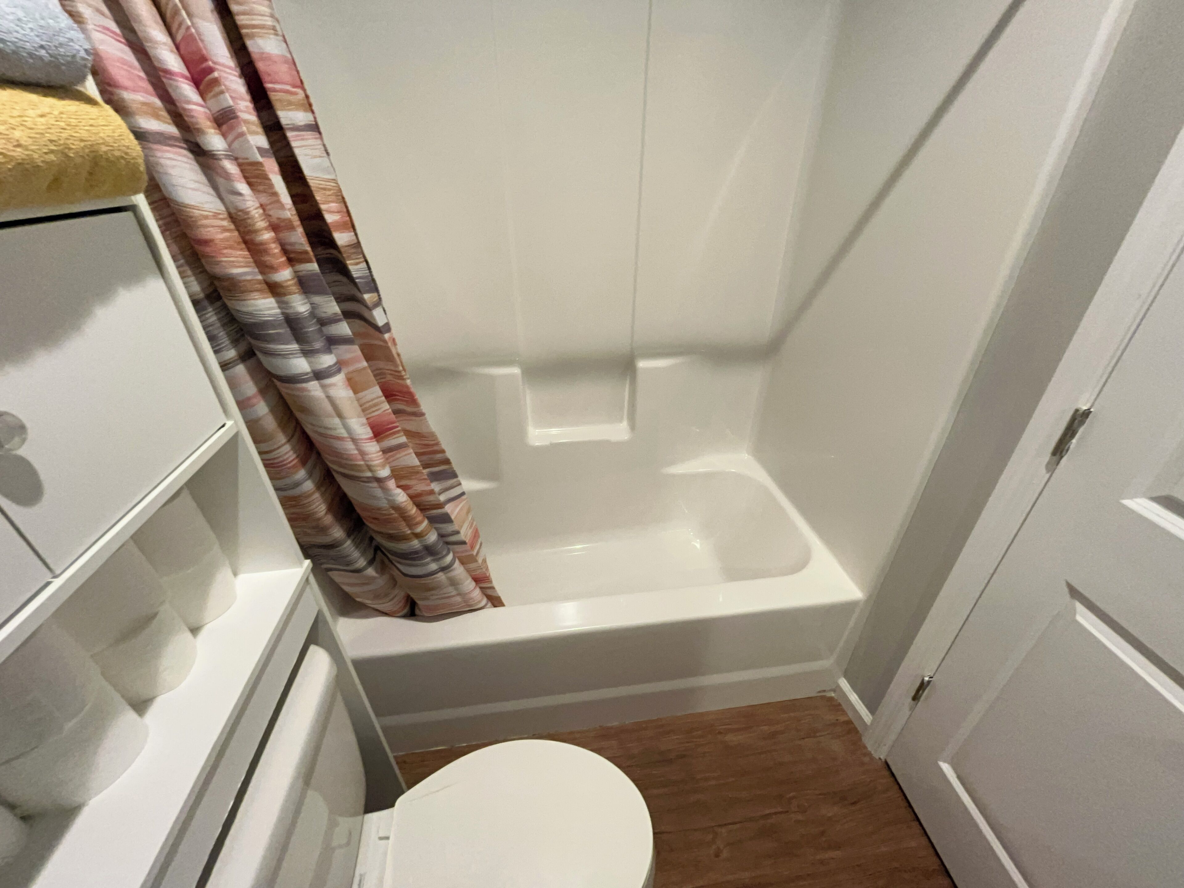 Ein kleines Badezimmer mit Dusche, Toilette und Ablagefläche für Handtücher.