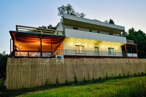 Uma casa moderna de dois andares com área externa coberta e cerca de madeira.