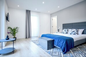 Quarto moderno com uma cama grande, uma mesinha, uma planta em vaso e vista para o exterior.