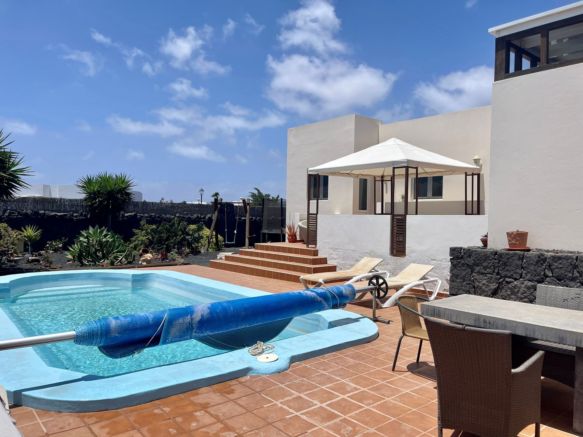 A swimming pool with lounge chairs and a covered seating area.