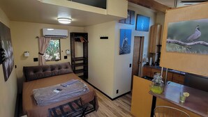 A compact room with a bed, a small kitchenette, and a window with curtains. - Dog friendly, peaceful 1 BR cottage w/ BA, AC on beautiful Lake Hodges (Escondido)