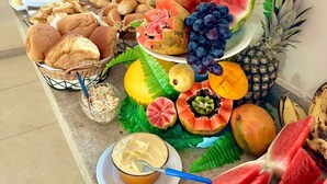 Een buffet met verschillende soorten eten, zoals brood, gebak, fruit en een kom soep.