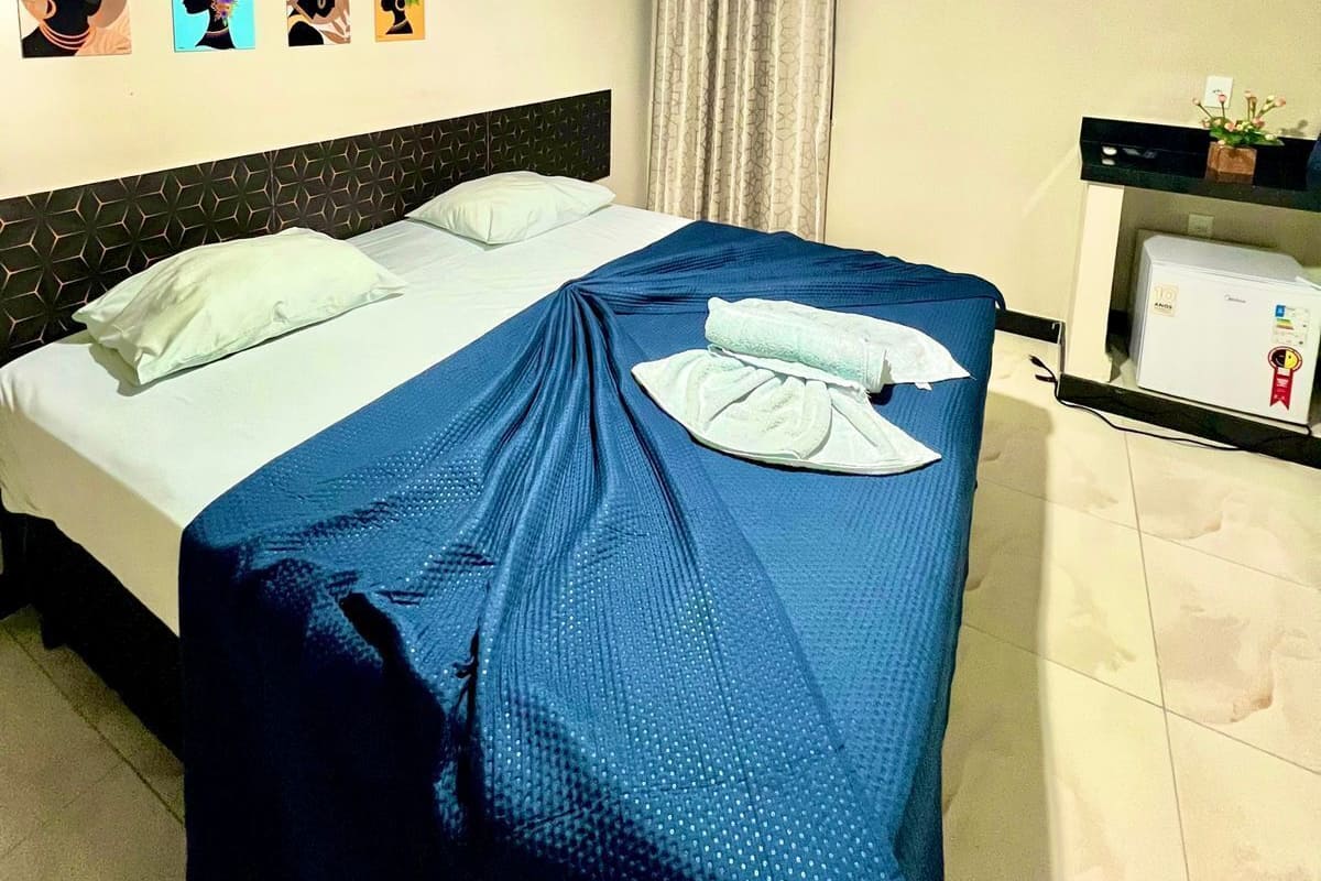 A hotel room with a bed, a desk, and a wall with artwork.