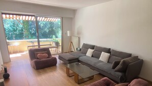 Un salon moderne avec un canapé gris, une table basse et un fauteuil rose.