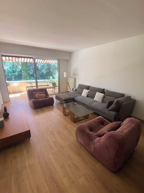 A modern living room with a grey sofa, a coffee table, and a pink armchair.