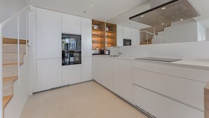 A modern kitchen with white cabinetry, a built-in oven, a microwave, and a stainless steel range hood. - Magnífico Apartamento con Piscina Privada y Vistas al mar en los Gigantes (Acantilados de Los Gigantes)