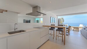 A modern kitchen with a large island, a dining area with bar stools, and a view of the sea. - Magnífico Apartamento con Piscina Privada y Vistas al mar en los Gigantes (Acantilados de Los Gigantes)