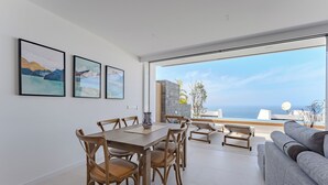 A modern living room with a dining area, large windows, and a view of the sea. - Magnífico Apartamento con Piscina Privada y Vistas al mar en los Gigantes (Acantilados de Los Gigantes)