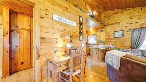 A wooden cabin interior with a dining area, a sofa, and a kitchen. - Scenic Oklahoma Studio Cabin on 80 Acres w/ Views! (Smithville)