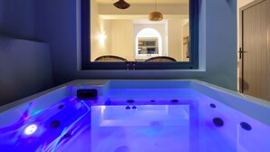 A modern bathroom with a bathtub, a window, and a view of a dining area. - Elia Caldera Suites (Santorini)