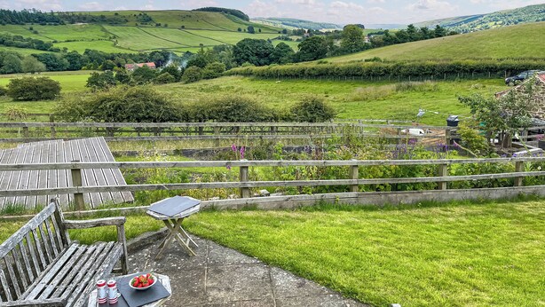 A wooden bench with a table and a bowl of strawberries and two cans of Pringles.