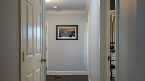 A hallway with a framed picture on the wall, a door on the left, and a closet on the right. - Charming 2-bedroom condo, 15 min from city with laundry & parking (Boston)