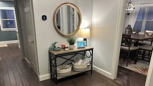 A hallway with a wooden console table, a mirror, and a lamp. - Charming 2-bedroom condo, 15 min from city with laundry & parking (Boston)