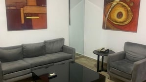 Ein modernes Wohnzimmer mit einem grauen Sofa, einem schwarzen Couchtisch und zwei abstrakten Bildern an den Wänden.