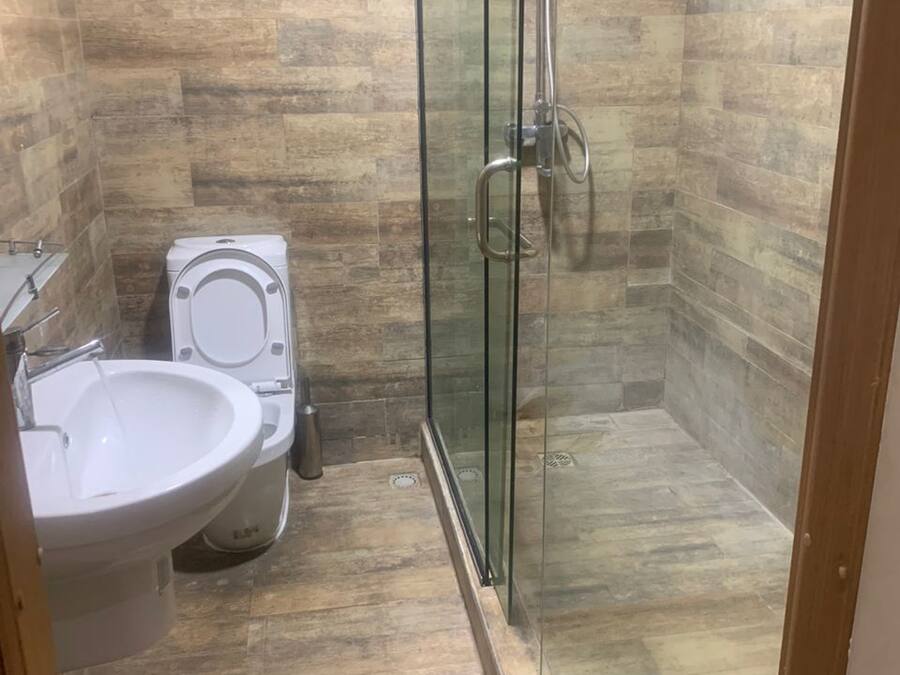 A bathroom with a glass-enclosed shower, a toilet, and a sink.