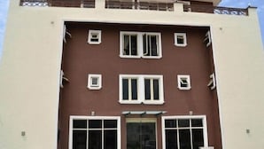 Ein Gebäude mit brauner Fassade, zahlreichen Fenstern und einem zentralen Eingang mit Glasüren.