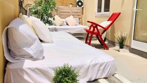 Ein Zimmer mit einem Bett, einem roten Sessel und einer kleinen Topfpflanze.